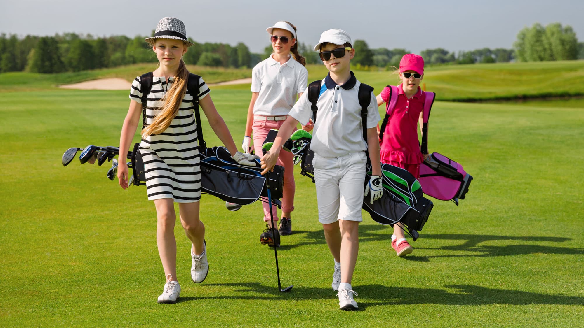 Four junior golfers walking together with their golf bags